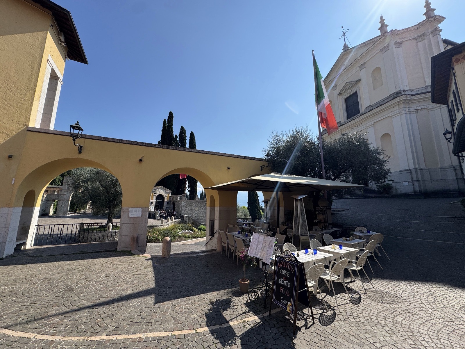 Set tables under the arches of Piazza dei Caduti, with the church in the background